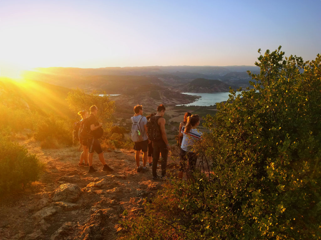Groupe d'amis de dos admirant un coucher de soleil lors d'une randonnée en montagne